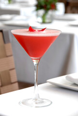 Strawberry martini garnished with rose petals on a restaurant table