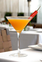 Orange martini garnished with a red chili on a restaurant table