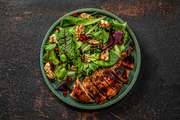 Grilled chicken breast fillet and mix salad with walnuts, pomegranate and balsamic sauce in a plate