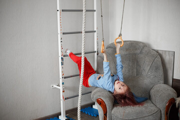 Little caucasian girl hanging on the wall bars exercising