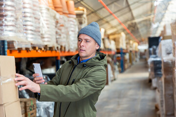 Caucasian man storekeeper using his phone to take photograph of pasteboard box.