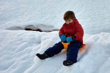 Fototapeta na wymiar enfant garçon fait de la luge sur la neige