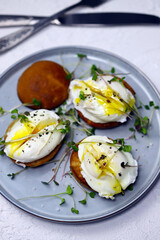 Selective focus. Poached eggs on buns with microgreens on a plate.