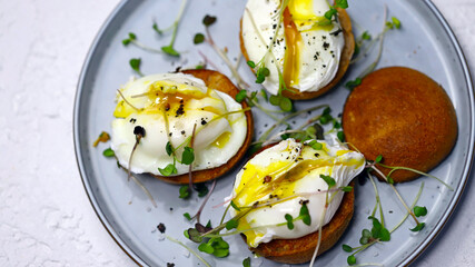 Selective focus. Poached eggs on buns with microgreens on a plate.