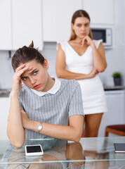 Two upset girls after quarrel at kitchen table