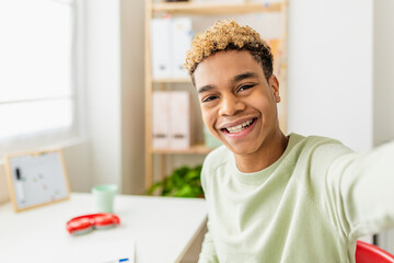 Smiling teenage boy taking selfie with smart phone in his room - Youth, generation z people and...