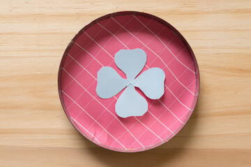 abstract or stylized paper flower inside a round metal container on wood