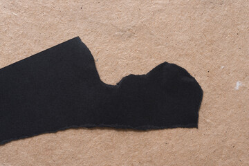 black paper with cut and torn edges on plain brown paper