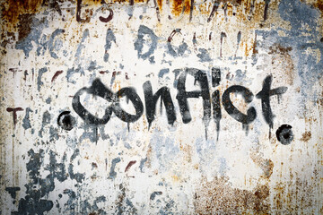 The word conflict spray painted on grungy concrete background. Weather washed.