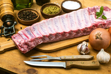 Raw ribs with spices on the table. On a rustic wooden table.