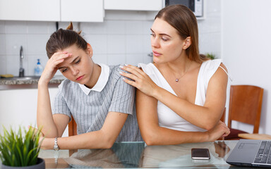 Portrait upset woman holding head after conflict, female friend tries reconcile