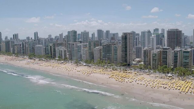 aerial view of Boa Viagem beach in Recife in the northeast region of Brazil with the sea buildings blue sky and beach umbrellas on the sand rotating from left to right