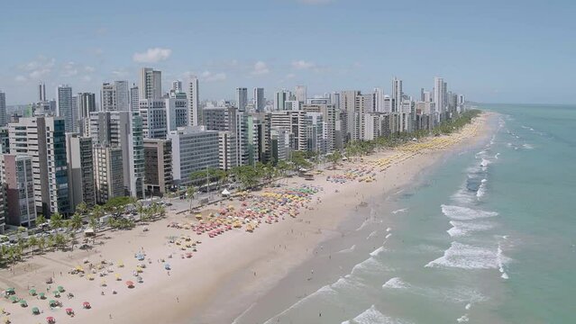 aerial view of Boa Viagem beach in Recife in the northeast region of Brazil with the sea buildings blue sky and umbrellas on the sand moving camera moving forward
