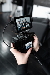 Hands of an operator holding a camera in his hand. In camera happy african american friends