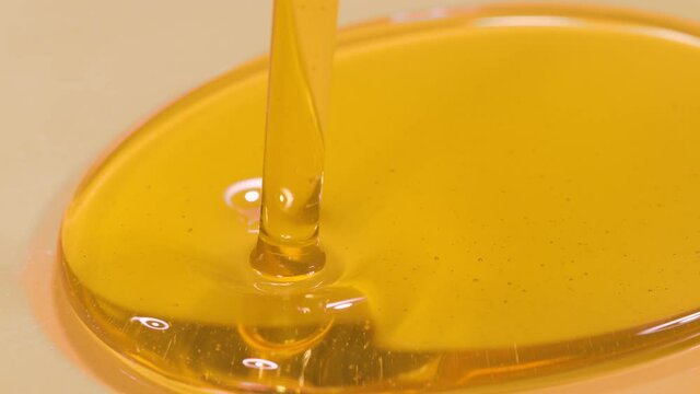 SLOW MOTION, MACRO, DOF: Delicious organic extra virgin olive oil flows into a deep dish. Shot of unrefined cold pressed walnut oil getting poured into a large container. Natural beauty product.