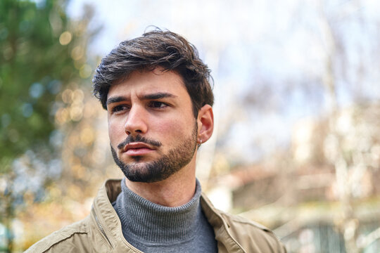 Bearded man in jacket standing in park
