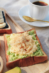 Breakfast with scrambled eggs, bread toasts, avocado and cup of coffee in morning light picnic blanket. delicious homemade breakfast