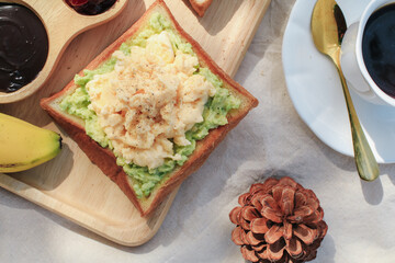 Breakfast with scrambled eggs, bread toasts, avocado and cup of coffee in morning light picnic blanket. delicious homemade breakfast