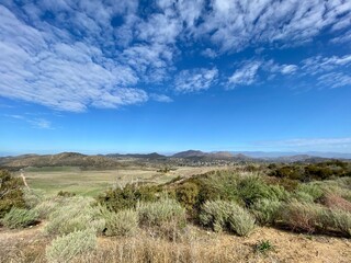 Wide view across scrubland towards mountains in Thousand Oaks area,  CA, seen from Point Mugu State Park. Typical Southern California suburban homes in the distance