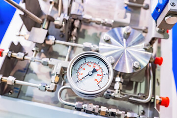 Pressure gauge on production equipment. Close-up pressure sensor. Fragment of production or laboratory equipment. Silver tubes next to mechanical pressure sensor. Industrial equipment.