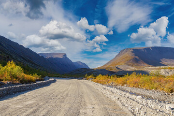 Dirt road. Highway in picturesque place. Not paved road for cars. Suburban landscape. Mountains on...