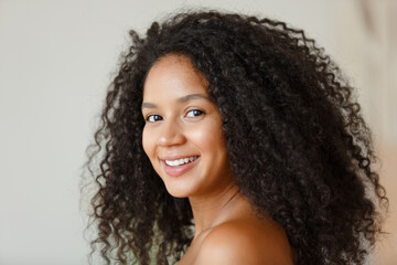 Portrait of an African American black woman. Beautiful woman at home. Girl with clean healthy skin. Lifestyle and cosmetics. Smiling beauty girl with afro curly hair