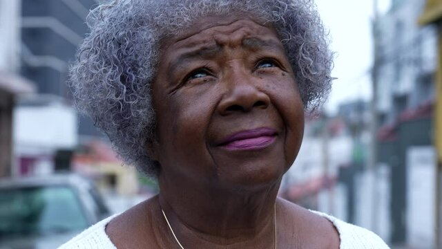 A contemplative senior black woman looking up at sky an African person eyes looks up