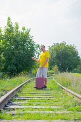 lonely man with a suitcase walking on the railroad