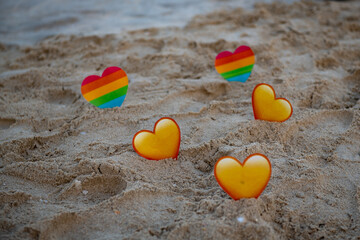 on the sea lgbt and yellow hearts in the sand stand