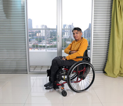 South East Asian Malay Middle Aged Disabled Man On Wheelchair Looking Sitting In Front Of Balcony Window Look Thumbs Up