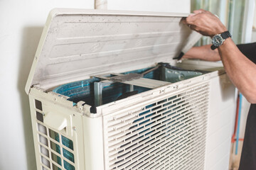 A technician opens up the top hatch of the outdoor compressor unit of a Split type air conditioner....