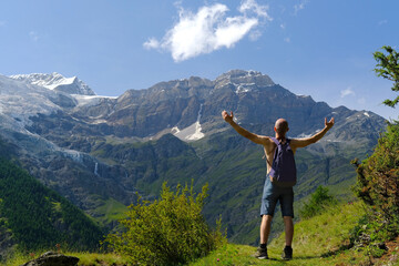young tourist with backpack, man stands on mountain, Swiss Alps with snow-capped Matterhorn peak visible in background, concept of hiking, rock climbing, active lifestyle, beauty of nature