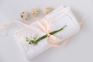 white linen napkin, trimmed with handmade lace, delicate snowdrop flower, three quail eggs lie on light table, concept of luxury serving spring breakfast, diet, Easter holiday