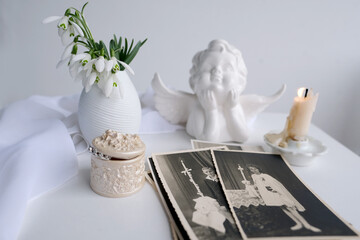 stack of vintage photos, pictures of children of first communion of 1950, candle is lit, spring flowers in vase, concept of family tree, genealogy, childhood memories