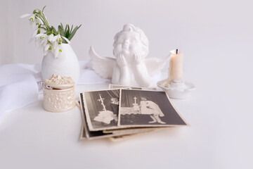 stack of vintage photos, pictures of children of first communion of 1950, candle is lit, spring flowers in vase, concept of family tree, genealogy, childhood memories