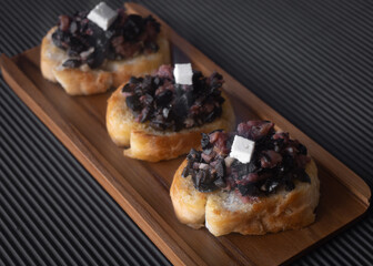 Bread slices with black olive tapenade and cheese 