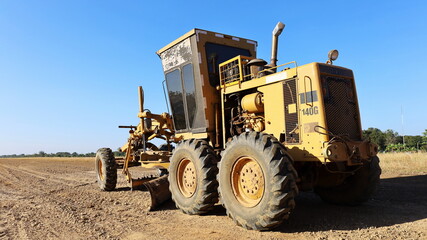 Obraz premium Graded on a new build road. Heavy equipment Grader is constructing a road or repair road on a blue sky background with copy space. Selective focus