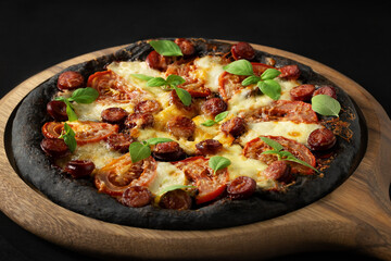 Black pizza with tomatoes, sausages, mozzarella and basil. Dough with healthy bamboo charcoal powder