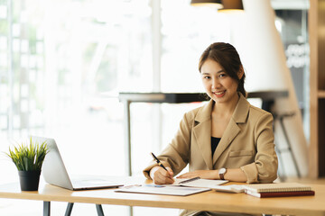 Image of young beautiful joyful woman smiling while working with laptop in office