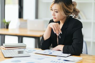 Pretty and charming asian businesswoman sitting happily smiling with laptop computer in the office.