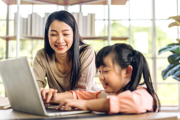 Mother and asian kid little girl learn and look at laptop computer reviewing lesson study with online education e-learning.student look for educational knowledge in homeschool at home.Education