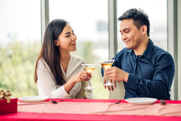 Romantic young asian happy love couple relaxing and talking together drinking wine glasses celebrating at dinner party lying on chair in the restaurant.date and anniversary concept