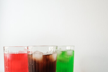 Glasses of soft drink with ice cubes and bubbles on wooden table kitchen background.