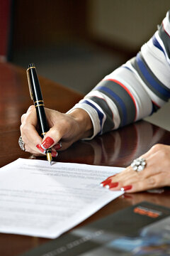 Mulher assinando um documento.
