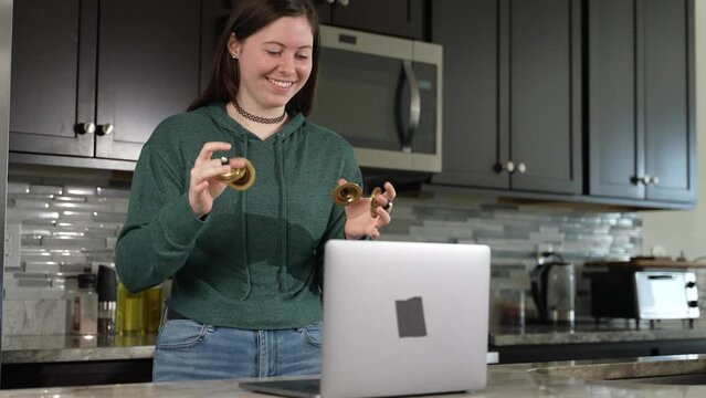 Smiling woman takes remote lesson to learn finger cymbals online on a laptop. Remote learning concept.