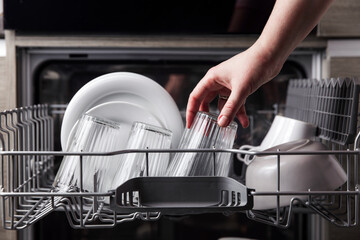 Close-up of female hand loading dished to, empty out or unloading from open automatic stainless...