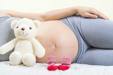 A tummy of a pregnant woman with red baby's bootees,Pregnancy health care preparing for baby...