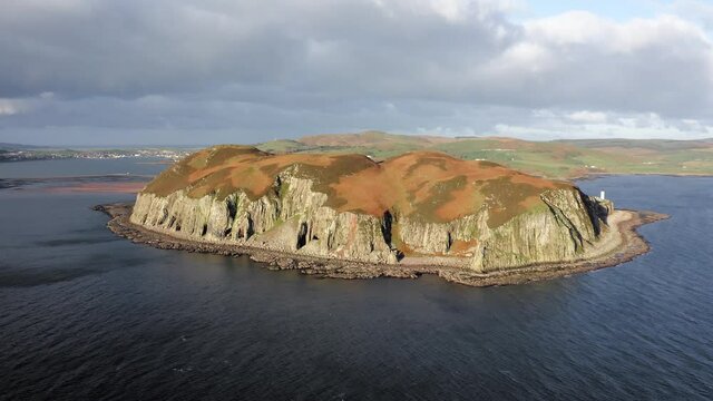 AERIAL - Epic shot of sunbathed Island Davaar, Kintyre, Scotland, reverse rising