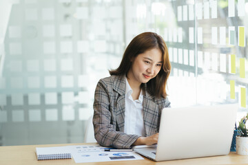 Asian woman working on a laptop computer,Working in the office with laptop concept,Young Asian woman starting a business using a laptop computer.