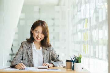 Asian accountant working on tablet, smiling on to camera.